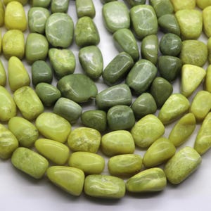 May include: A collection of tumbled, polished gemstone beads in various shades of lime green, olive, and chartreuse. The beads are irregularly shaped, smooth, and have a glossy finish, arranged in a dense cluster showing natural color variations.