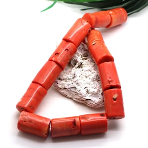 Könnte beinhalten: Ein Strang aus zylindrischen, leuchtend orange-roten Korallenperlen, die in einer Dreiecksform angeordnet sind. Die Perlen weisen natürliche Oberflächenstrukturen, Variationen in der Farbintensität und kleine organische Vertiefungen auf.