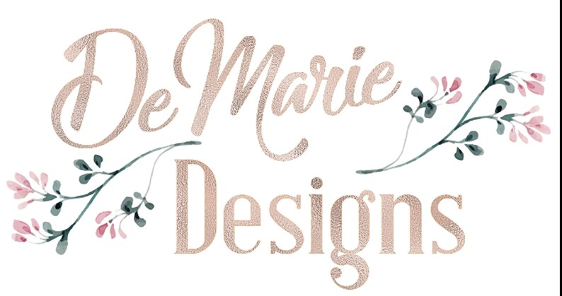 May include: The logo features the text "De Marie Designs" in a textured, rose gold font. Delicate watercolor floral elements in pink and green accent the text, set against a white background.