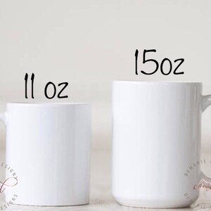 May include: Two white ceramic mugs, one labeled "11 oz" and the other "15 oz". Both mugs have a simple, clean design with a curved handle. The mugs are set against a plain background, highlighting their shape and size.