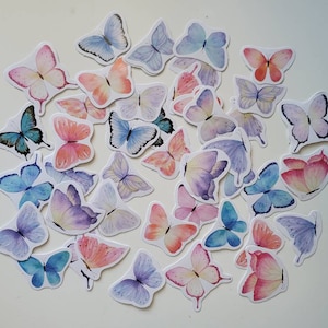 May include: A collection of colorful butterfly stickers with watercolor designs. The stickers feature butterflies in shades of blue, pink, purple, and orange.