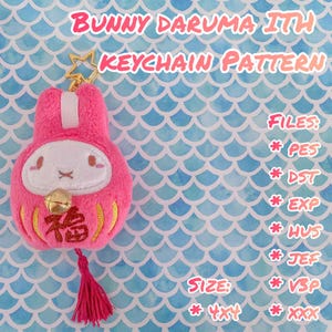 May include: A pink Bunny Daruma ITH keychain pattern with a gold star-shaped clasp. The keychain features a white face, a gold bell, and a red tassel. Text on the image includes "BUNNY DARUMA ITH KEYCHAIN PATTERN" and file types.