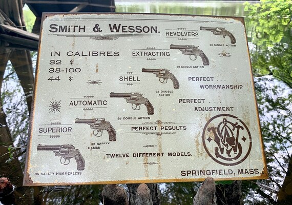 SMITH & WESSON REVOLVERS;ANTIQUE-STYLE METAL WALL SIGN 41X31cm/VARIOUS CALIBRES 