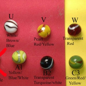 Pu&ograve; includere: Una collezione di biglie di diversi colori e motivi, etichettate con lettere dalla S alla X. Le biglie sono disposte in due file su uno sfondo rosso e giallo. Ogni biglia &egrave; etichettata con una lettera e una descrizione del suo colore e del suo motivo.