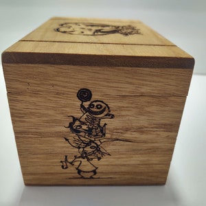May include: Wooden box with a hinged lid. The box is decorated with a laser-engraved image of characters from the movie "The Nightmare Before Christmas".