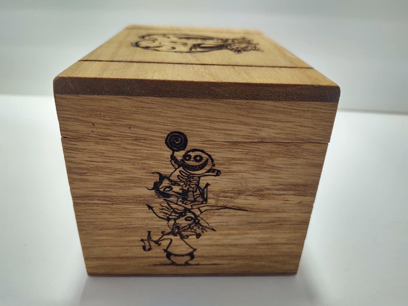 May include: Wooden box with a hinged lid. The box is decorated with a laser-engraved image of characters from the movie "The Nightmare Before Christmas".