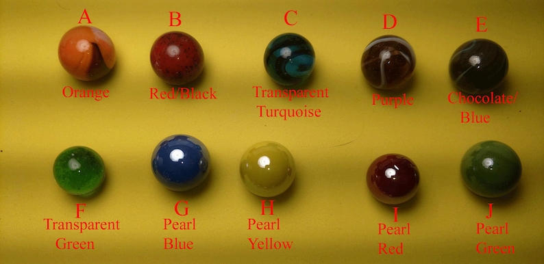 Pu&ograve; includere: Dieci biglie di diversi colori e motivi, etichettate dalla A alla J. Le biglie sono disposte in due file di cinque. Le biglie sono tutte pi&ugrave; o meno della stessa dimensione e hanno un diametro di circa 2,5 cm.
