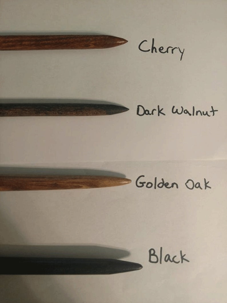 Pu&ograve; includere: Quattro pioli di legno in diverse macchie di legno: ciliegio, noce scuro, rovere dorato e nero. I pioli sono disposti verticalmente su una superficie bianca con i nomi delle macchie di legno scritti accanto a ciascun piolo.
