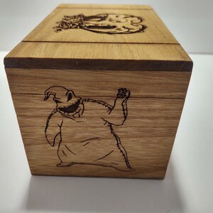 May include: A wooden box with a hinged lid. The box is decorated with an engraved image of a character from the movie "The Nightmare Before Christmas".