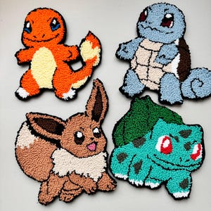 May include: Four handmade felt Pokemon characters.  The characters are Bulbasaur, Charmander, Squirtle, and Eevee.  The characters are all in a sitting position and are made with different colored felt.