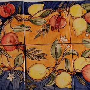 Puede incluir: Un conjunto de seis azulejos de cerámica que representan una vid estilizada con granadas y limones. Los azulejos están pintados en tonos de amarillo, rojo, verde y azul sobre un fondo azul.