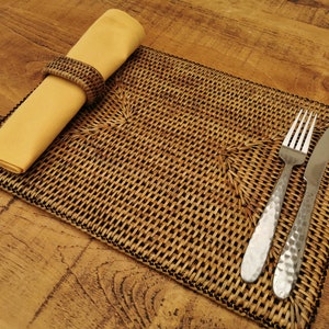 May include: A woven rattan placemat with a yellow napkin and a silver fork and knife.