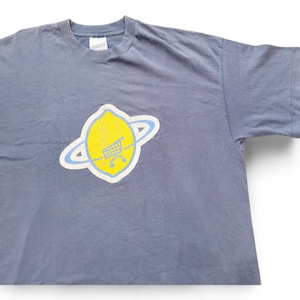 May include: A gray t-shirt with a yellow lemon graphic. The lemon has a blue ring around it and a shopping cart inside.