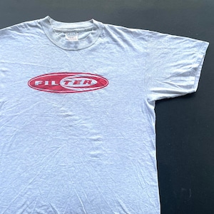 May include: A gray t-shirt with a red oval logo that says "FILTER" in white letters.