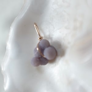 May include: A small cluster of purple agate stones wrapped in gold wire, forming a pendant.