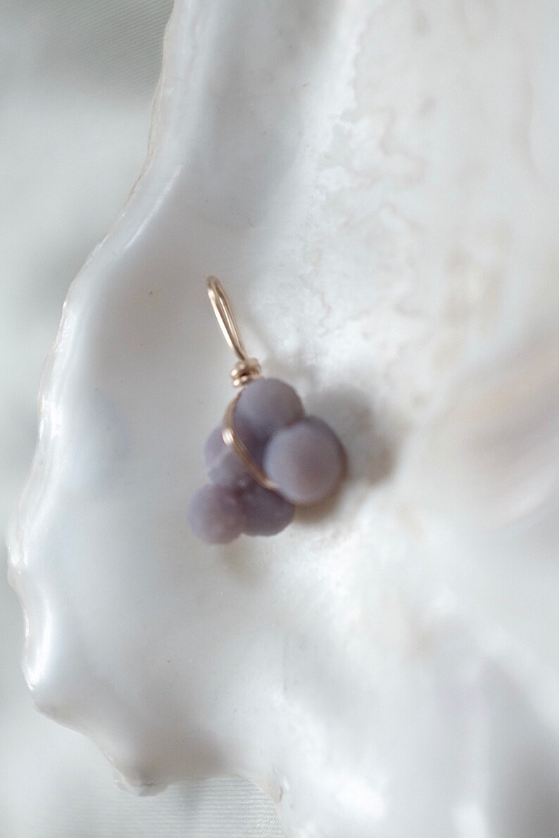 May include: A small cluster of purple agate stones wrapped in gold wire, forming a pendant.