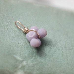May include: A silver wire wrapped pendant featuring three lavender-colored, irregularly shaped stones.