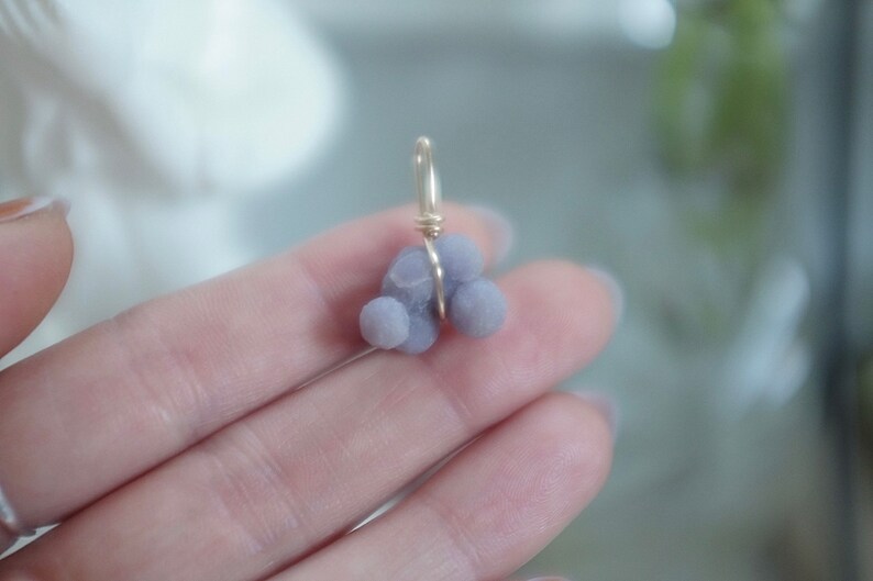 May include: A purple agate pendant with a gold wire wrap. The agate is a cluster of small, round stones.
