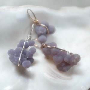 May include: Two pairs of earrings featuring clusters of purple agate stones wrapped in silver and gold wire.