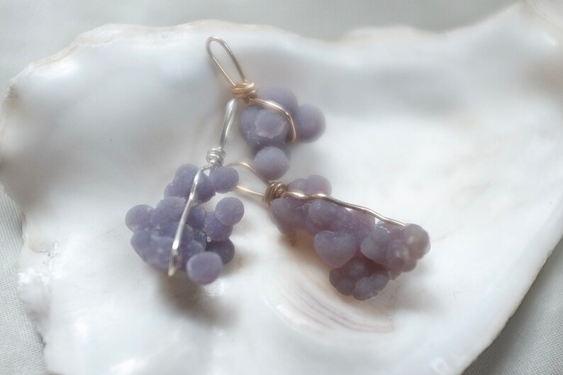 May include: Two pairs of earrings featuring clusters of purple agate stones wrapped in silver and gold wire.