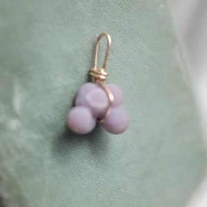 May include: A purple agate pendant with a gold wire wrap. The agate is a cluster of three rounded stones.