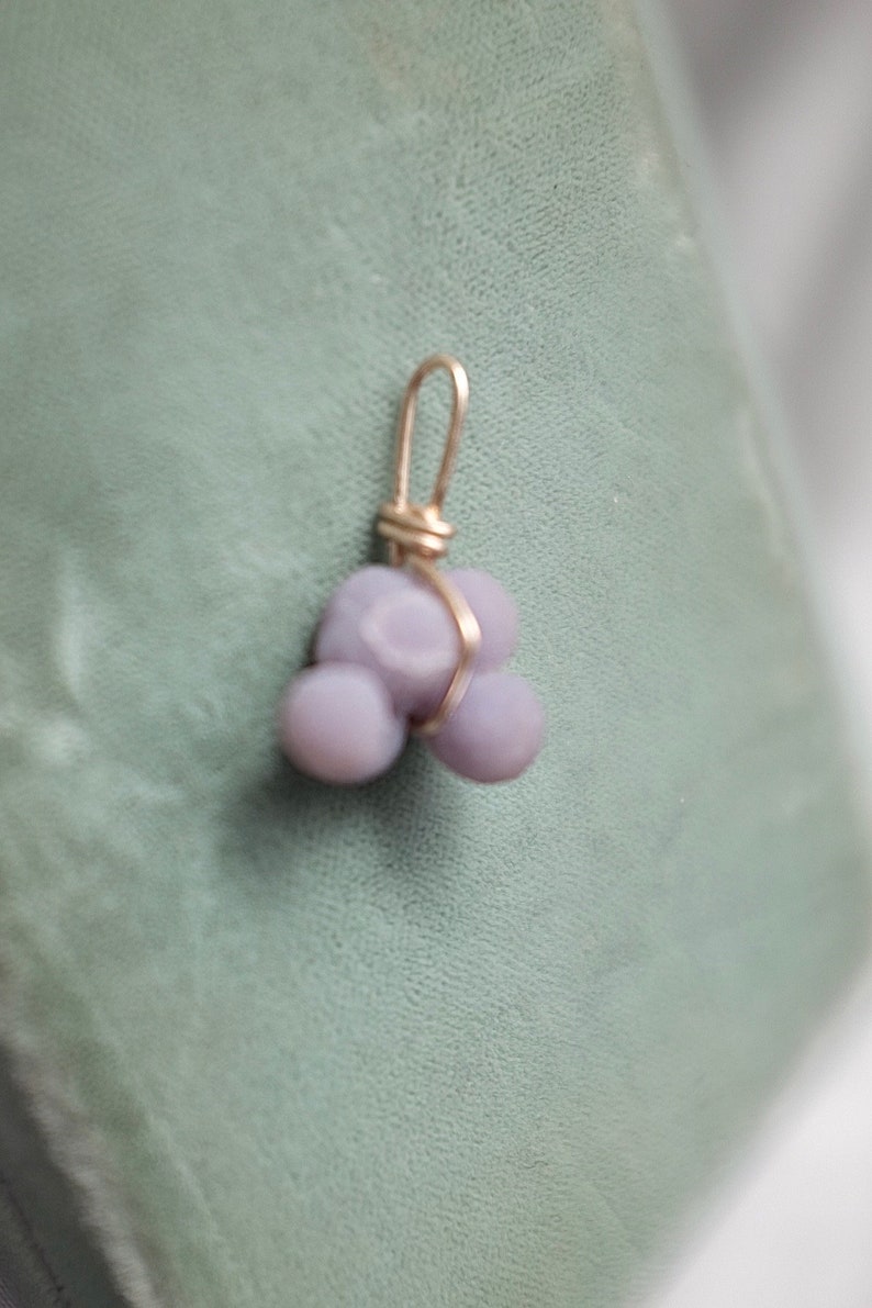 May include: A purple agate pendant with a gold wire wrap. The agate is a cluster of three rounded stones.