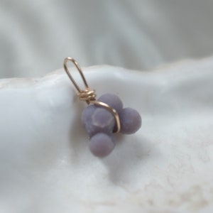 May include: A purple agate pendant with a gold wire wrap. The agate is a cluster of small, round stones.