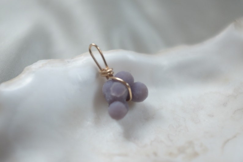 May include: A purple agate pendant with a gold wire wrap. The agate is a cluster of small, round stones.