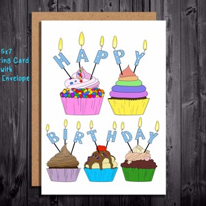 Puede incluir: Tarjeta de felicitación de 5x7 con sobre kraft. Presenta ilustraciones coloridas de cupcakes con velas que deletrean "HAPPY BIRTHDAY". Los cupcakes tienen diferentes glaseados y coberturas.