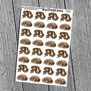 May include: A sheet of stickers featuring multiple images of coiled snakes in shades of brown and tan. The stickers are arranged in rows and columns. The sheet has the text "Dallington's 832" printed on it, along with a website address.