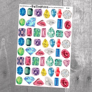 May include: A sheet of colorful gem stickers with various shapes and sizes. The stickers are on a white background and feature a variety of colors, including red, blue, green, purple, and yellow.