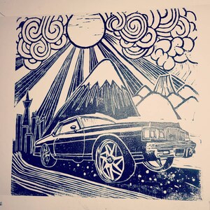 May include: A black and white woodblock print of a vintage car driving through a mountain landscape. The car is a classic American sedan with a large, rounded body and a long hood. The mountain landscape is stylized and features a sun with rays emanating from it.