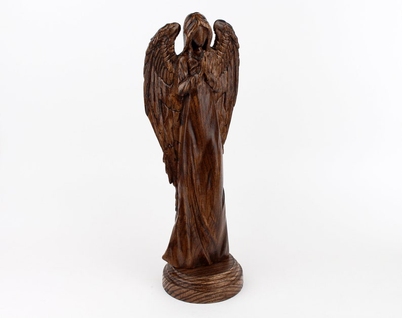 May include: A wooden angel figurine with wings outstretched and a flowing robe. The angel is carved from dark wood and has a detailed face.