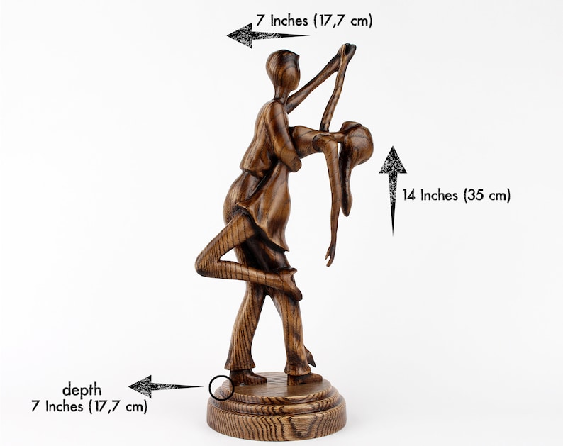 May include: A wooden sculpture of a couple dancing, the man holding the woman in a dip. The sculpture is 14 inches tall and 7 inches wide.