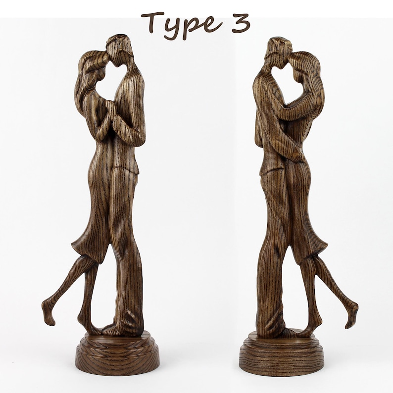 May include: A wooden sculpture of a couple embracing. The sculpture is made of dark wood and has a natural wood grain finish. The couple are standing on a wooden base.