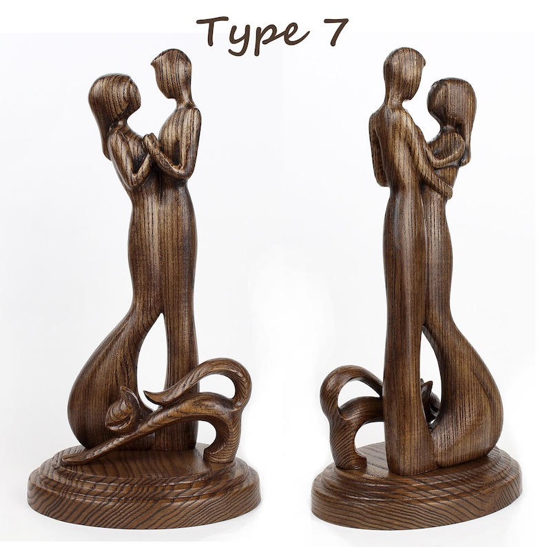 May include: A wooden sculpture of a couple embracing, with the woman's arm around the man's waist. The sculpture is dark brown and has a detailed wood grain pattern. The couple are standing on a base with a decorative design. The sculpture is labelled "Type 7".