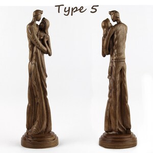 May include: A wooden sculpture of a couple embracing, carved in a realistic style. The sculpture is made of dark brown wood and has a natural wood finish. The couple are standing on a wooden base.