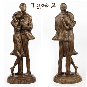 May include: A wooden sculpture of a couple embracing, with the man on the left and the woman on the right. The sculpture is finished in a dark brown stain and has a natural wood grain. The couple are standing on a wooden base.