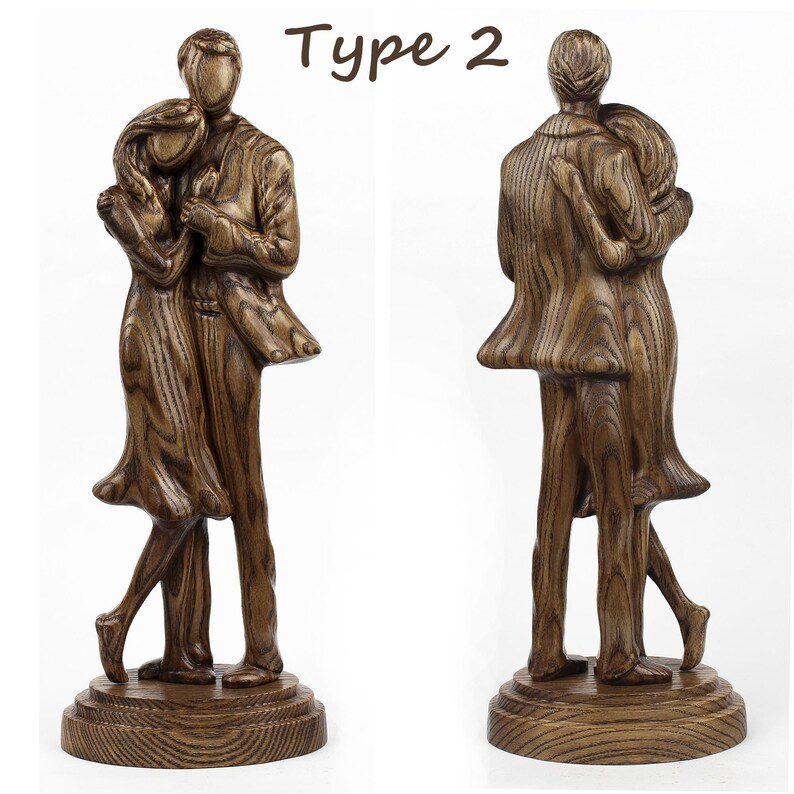 May include: A wooden sculpture of a couple embracing, with the man on the left and the woman on the right. The sculpture is finished in a dark brown stain and has a natural wood grain. The couple are standing on a wooden base.