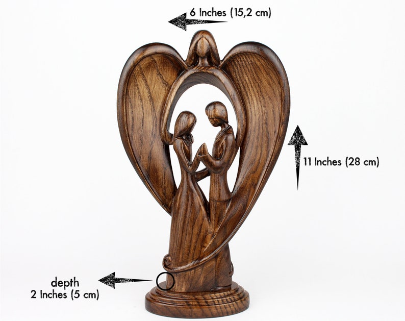 May include: A wooden sculpture of a couple standing inside a heart-shaped frame with angel wings. The sculpture is 11 inches tall, 6 inches wide, and 2 inches deep.