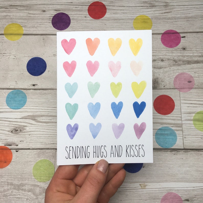 May include: A white card with a rainbow of watercolour hearts and the text "Sending Hugs and Kisses".