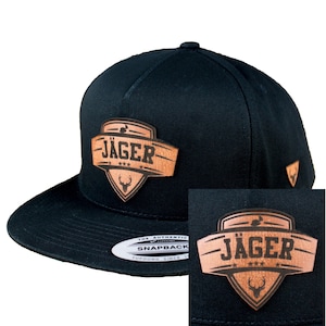 Könnte beinhalten: Schwarze und braune Baseballkappe mit einem Lederpatch, auf dem "Jäger" mit drei Sternen und einem Hirschkopf-Logo steht.