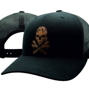 May include: Black trucker hat with a brown skull and crossbones design. The skull is wearing a cap and the crossbones are wrenches.