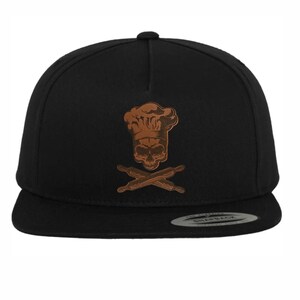 May include: Black and brown baseball cap with a skull wearing a chef's hat and crossed rolling pins.