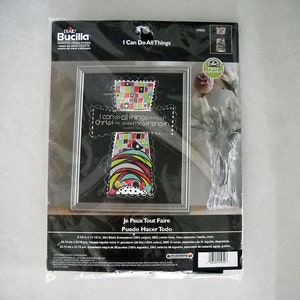 May include: A counted cross stitch kit featuring a colorful mosaic cross with the text "I can do all things through Christ who gives me strength." The kit includes black Aida fabric, DMC floss, needles, chart, and instructions. The kit is 8.5 inches by 12.12 inches.