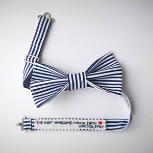 Könnte beinhalten: Eine blaue und weiße gestreifte Fliege mit verstellbarem Band. Das Band hat ein weißes Etikett mit dem Text "THE MOST HANDSOME MAN ON EARTH LOVE YOU, EMILY" und einem roten Herzen.