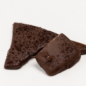 May include: Two pieces of dark chocolate bark with a sprinkle of coffee grounds on top.