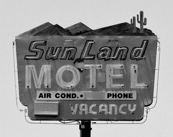 Fotografía cinematográfica en blanco y negro de un antiguo letrero de neón de un motel en la carretera en Arizona