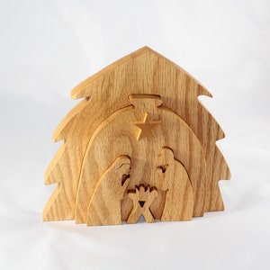 May include: Wooden nativity scene featuring a tree-shaped structure with layered cutouts. The scene includes figures of Mary, Joseph, and baby Jesus, with a star above. The wood has a natural, light brown color.