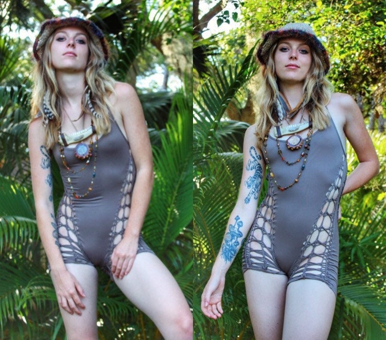May include: A woman wearing a brown crocheted bodysuit with cutouts and a brown crocheted hat. She is wearing multiple necklaces with beads and charms. She has a tiger tattoo on her arm.
